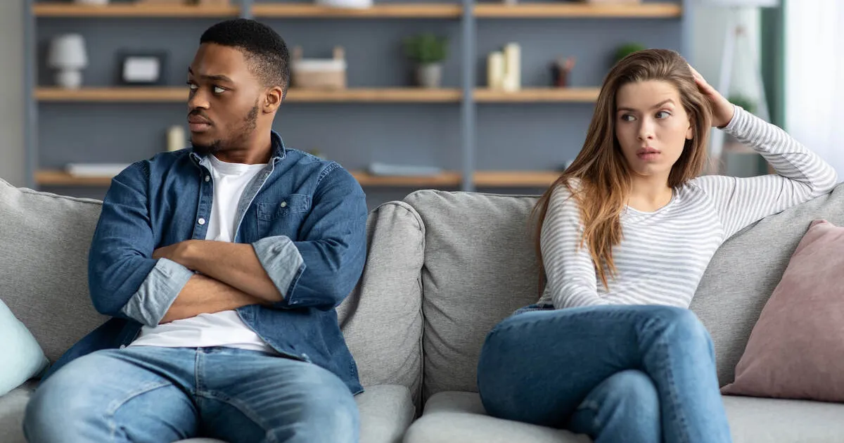 An unhappy couple faces away from each other on a couch in a professional office setting.