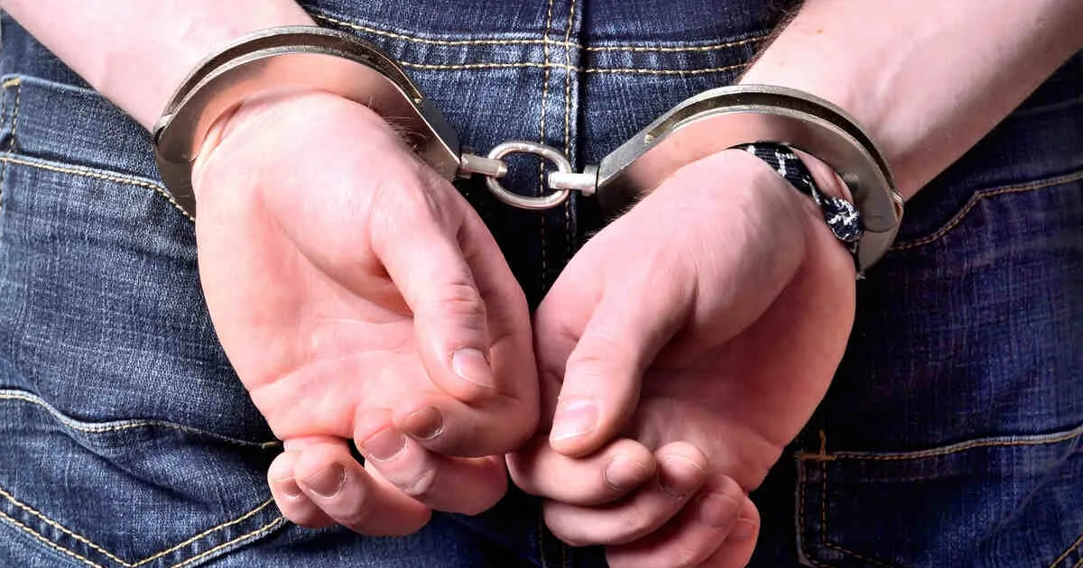 Close-up of the wrists of a man being detained in handcuffs.