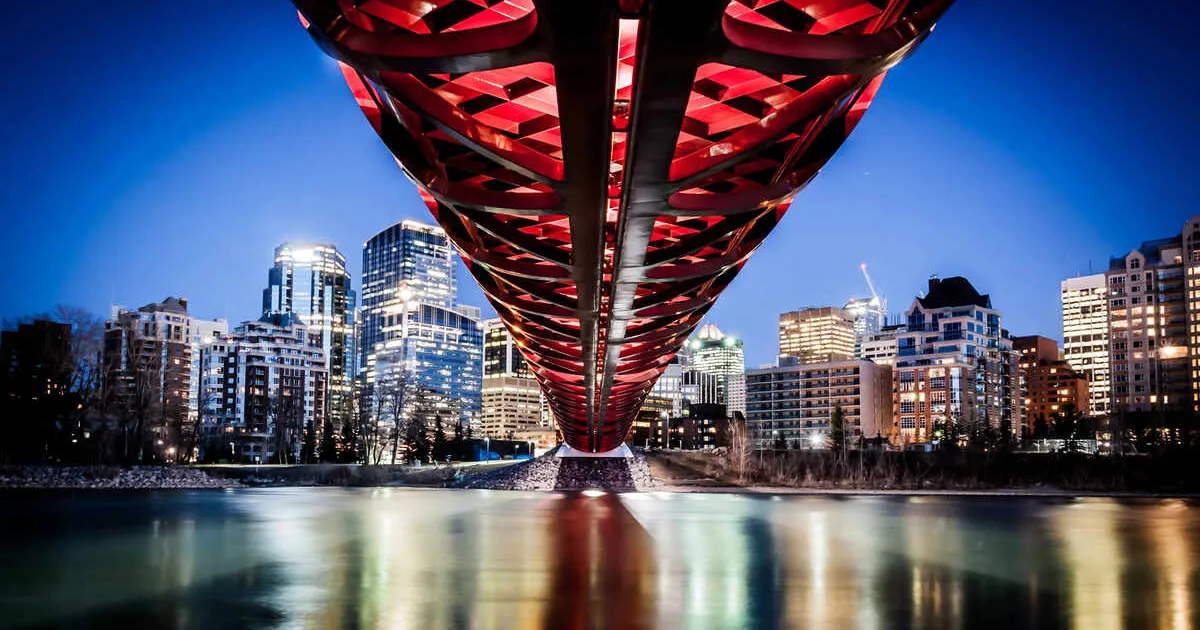 Downtown Calgary skyline as viewed from directly underneath a vibrant red pedestrian bridge.