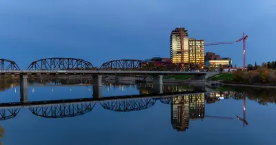 A bridge over the river in downtown Saskatoon, reflected in calm water at dawn